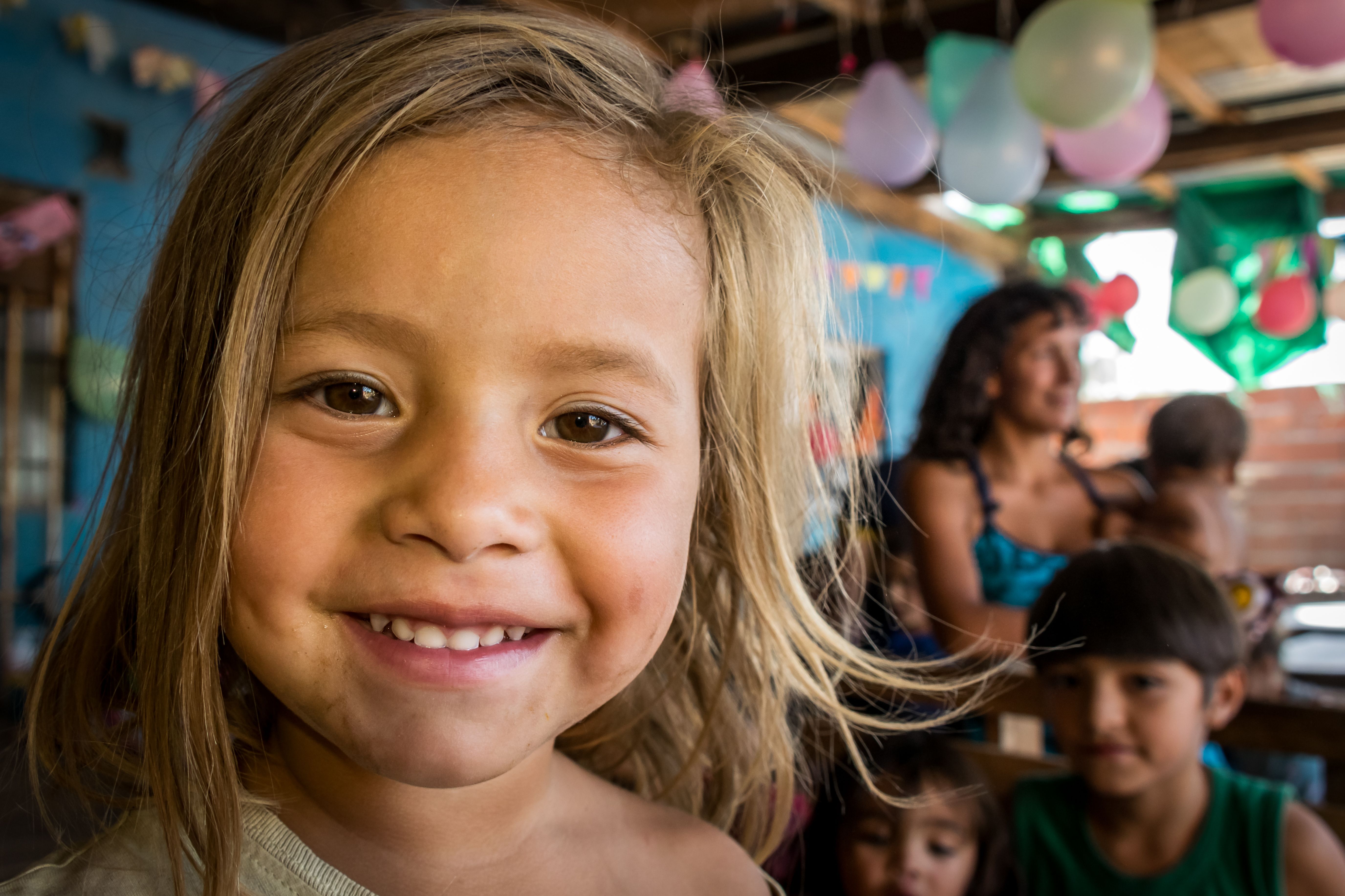 A smiling child at a lively community event with balloons in Argentina.