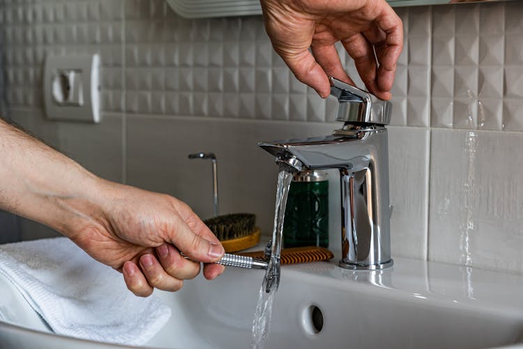 Person Washing Shaver On Sink