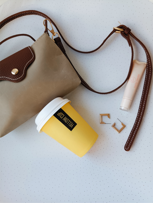 Free Minimalist flat lay of a handbag, yellow coffee cup, beauty product, and earrings. Stock Photo