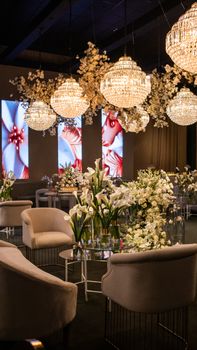Glamorous indoor event space with chandeliers and elegant floral arrangements.