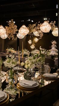 Chic wedding reception setup featuring elegant floral arrangements and glowing chandeliers.