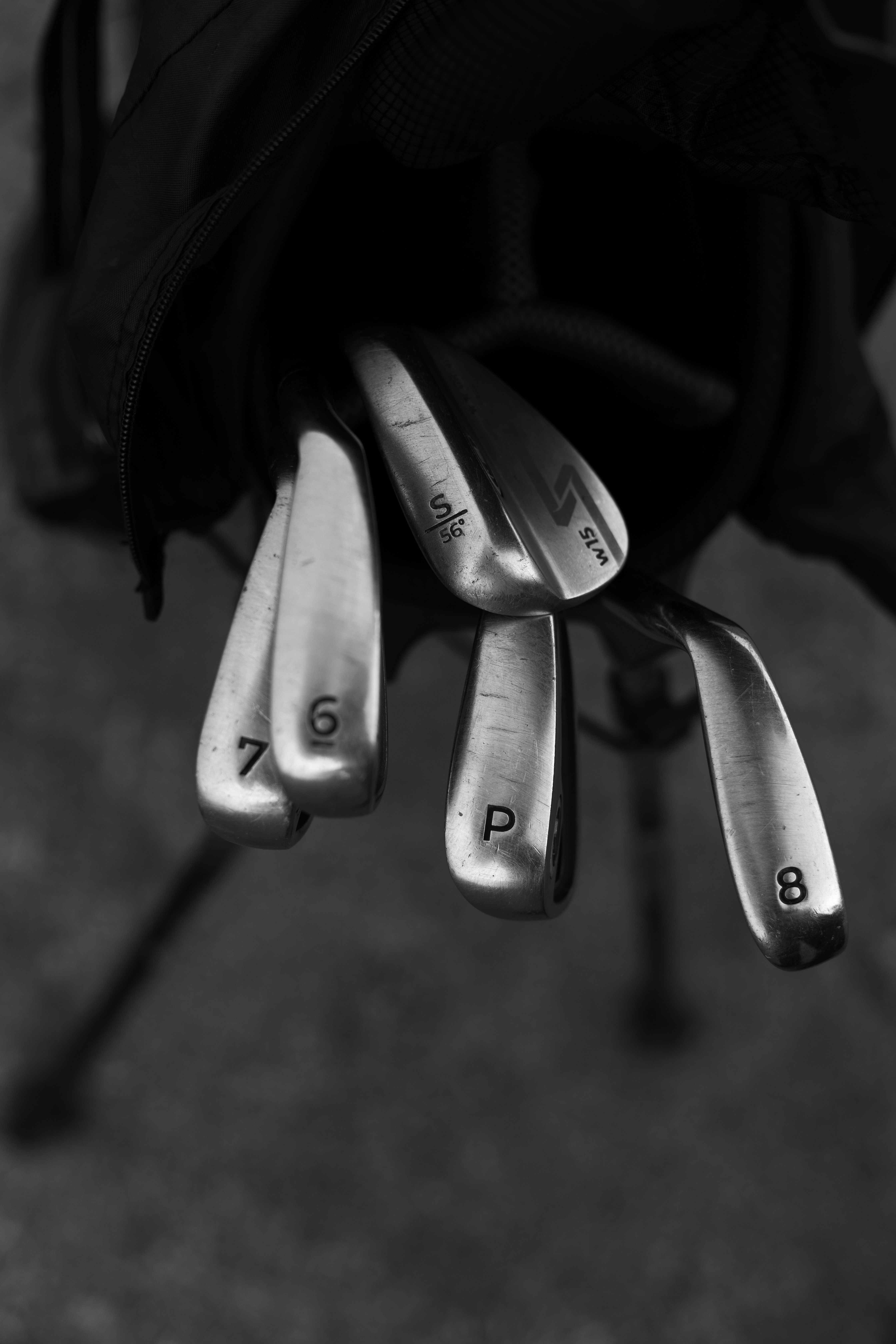 Monochrome photo of golf clubs in a bag, showcasing various irons.