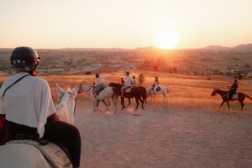 Free Riders enjoy a serene horseback adventure in Cappadocia at sunset, surrounded by beautiful landscapes. Stock Photo