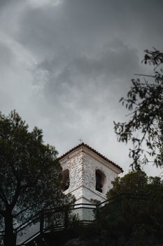 Moody view of the historic bell tower in Guadalest, surrounded by trees