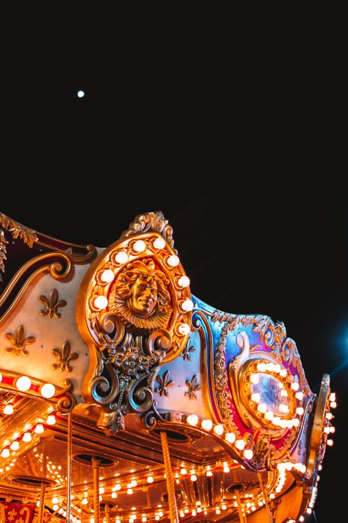 Free A beautifully illuminated carousel with intricate detailing against a dark night sky. Stock Photo