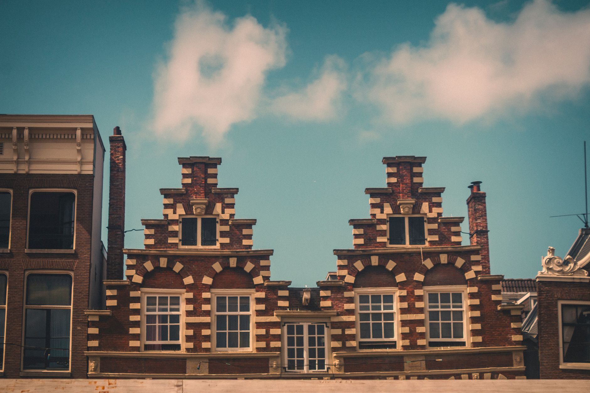 Iconic gabled buildings in Amsterdam, showcasing traditional Dutch architectural style under a clear blue sky.