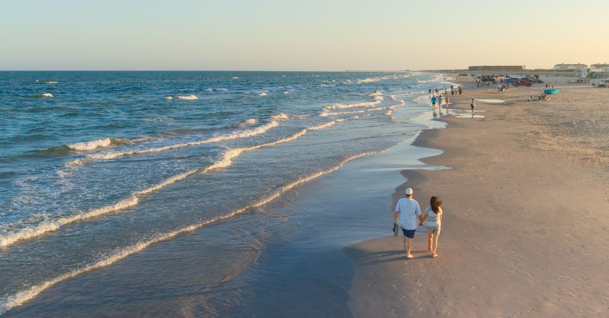 Aerial view of a couple walking on the beach in Corpus Christi, Texas, during a beautiful sunset