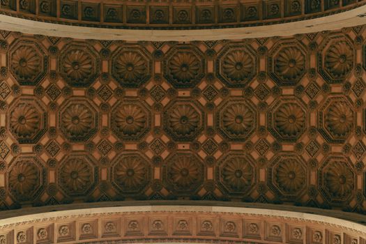 Detailed view of an ornate architectural ceiling featuring floral and geometric patterns in warm tones.
