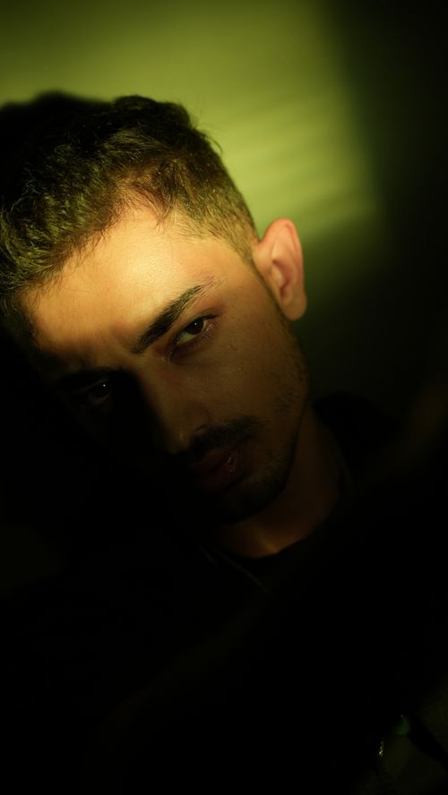 Free Dramatic portrait of a young man in low-key lighting, creating a cinematic and moody atmosphere. Stock Photo
