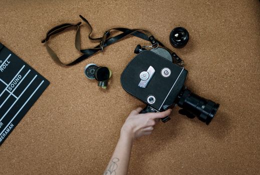 A vintage analog camera and clapboard on a cork surface, representing classic cinematography.