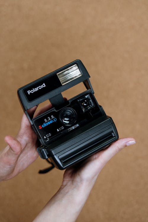 Black Polaroid Instant Camera on Persons Hand