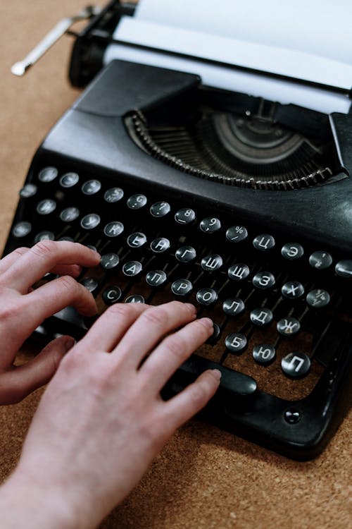 Person Holding Black Typewriter on Brown Table