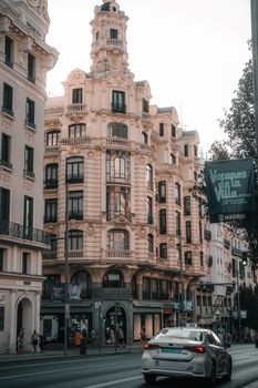 Street view of historic buildings in Madrid with ornate details and urban traffic.
