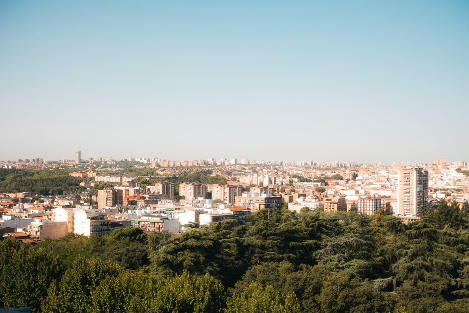 Elevated panoramic view of Madrid's urban landscape with lush greenery and clear skies.