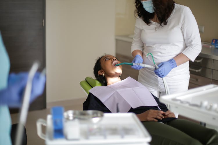 Dental Assistant Curing Teeth Of Black Woman