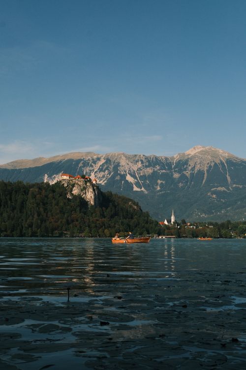Free Peaceful view of Lake Bled with a distant castle and mountains under a clear sky. Stock Photo