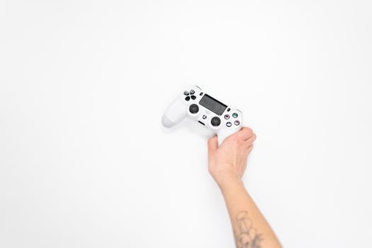 A white gaming controller held by a hand against a minimal white background, perfect for tech and gaming themes.