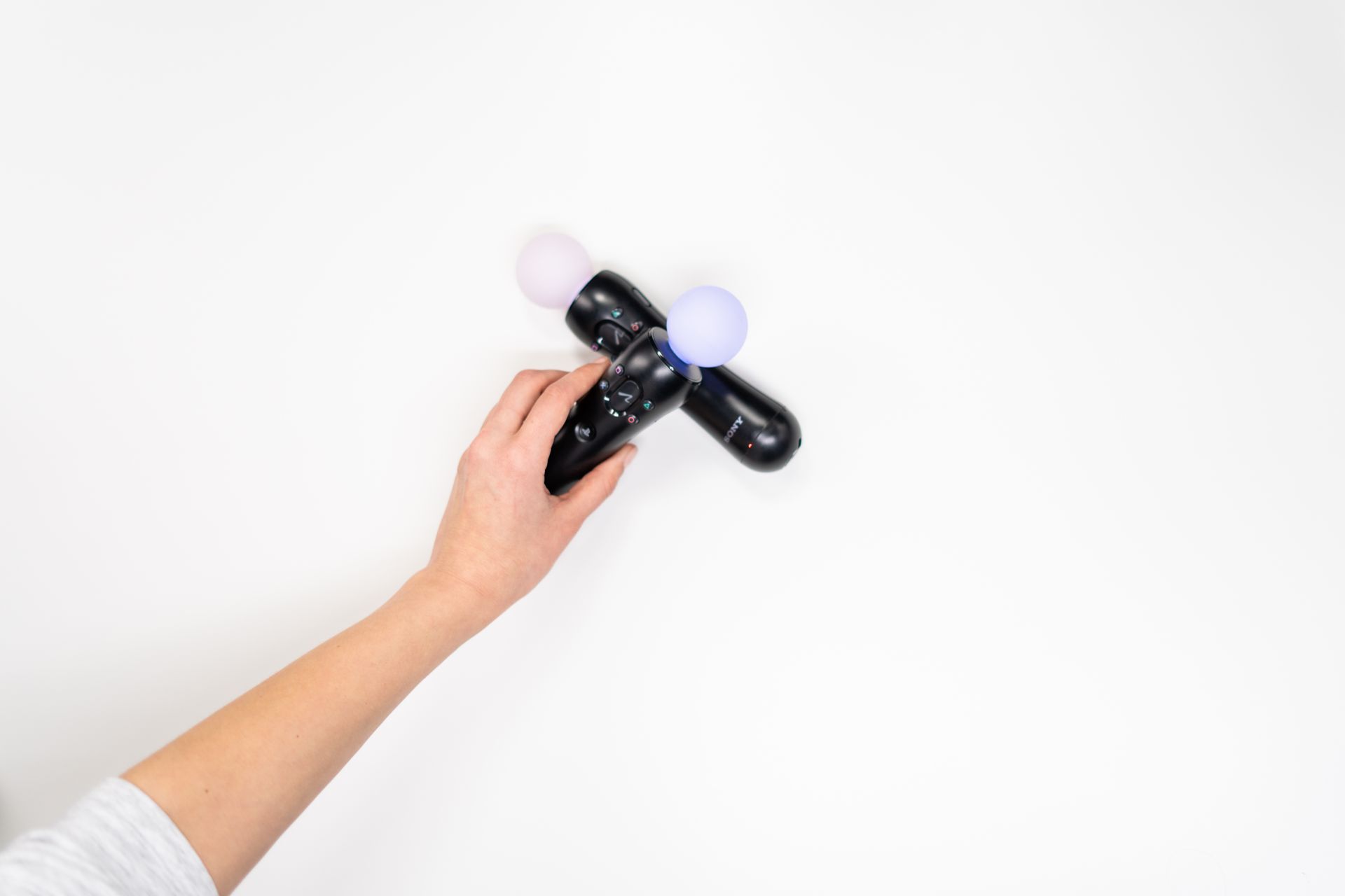 Hand holding a motion controller on a white surface, ideal for gaming concepts.