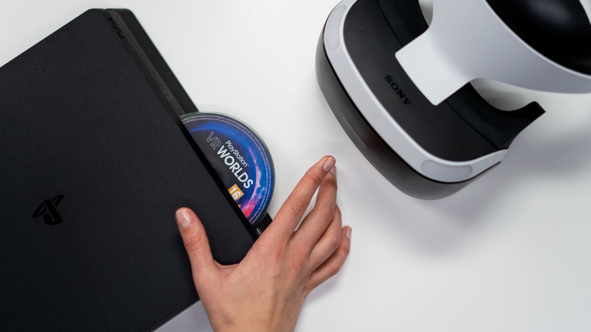 A close-up of a hand inserting a game disc into a PlayStation console, with no faces in the frame, a real stock photo chosen because the whole fight is about discs versus download codes in GTA 6's boxed edition