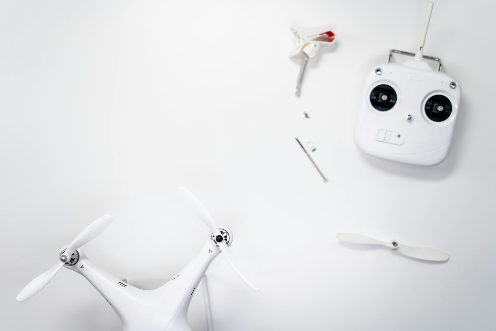 A flat lay of a drone kit including a controller and spare propellers on a white background.