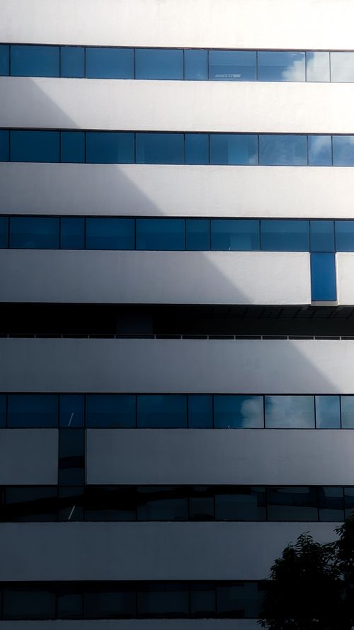 Free Abstract view of a modern building with glass windows reflecting sky in Bengaluru, India. Stock Photo