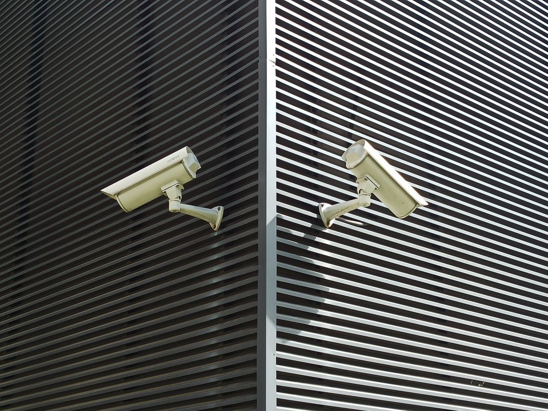 Security cameras mounted on slatted wall for surveillance