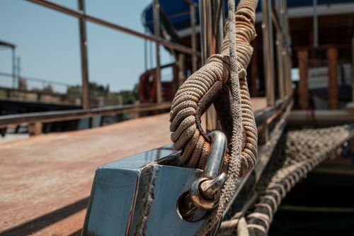 Free Detailed shot of a sturdy nautical rope fastened to a metal clamp on a boat deck, evoking a rustic and maritime theme. Stock Photo