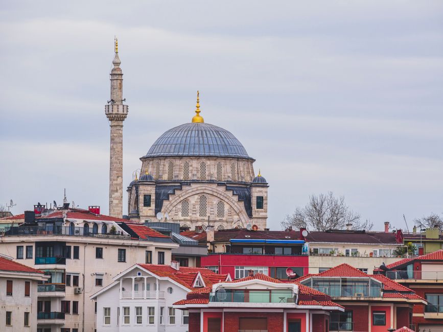 View of an Ottoman mosque and minaret amid urban Istanbul architecture, showcasing cultural heritage.