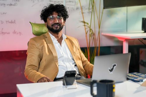 Free Young professional in a stylish office with laptop, phone, and vibrant decor. Stock Photo