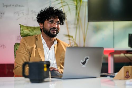 Free Professional man in casual business attire working on laptop in a modern office setting. Stock Photo