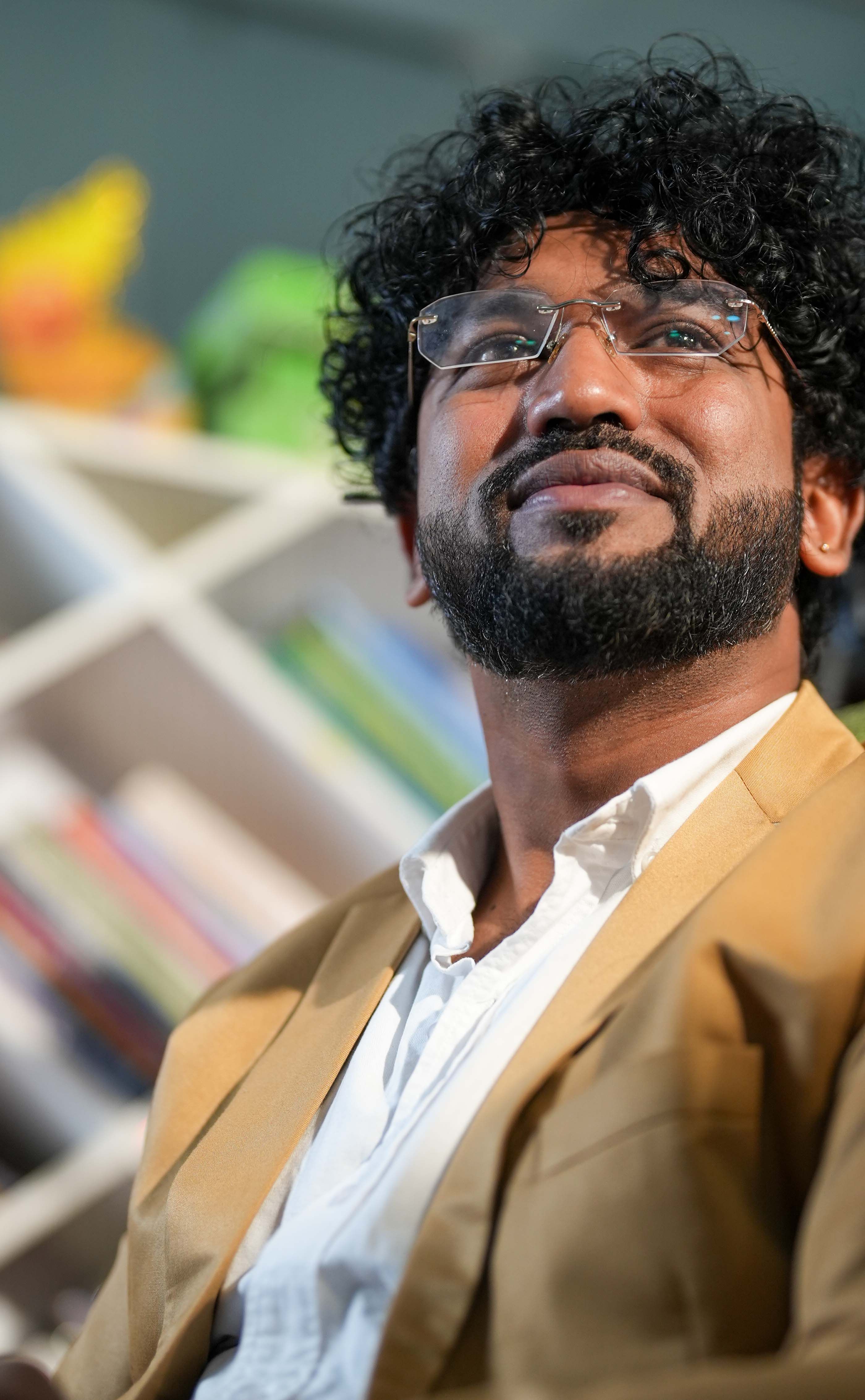 Portrait of a confident man in a blazer with books in the background, exuding success.