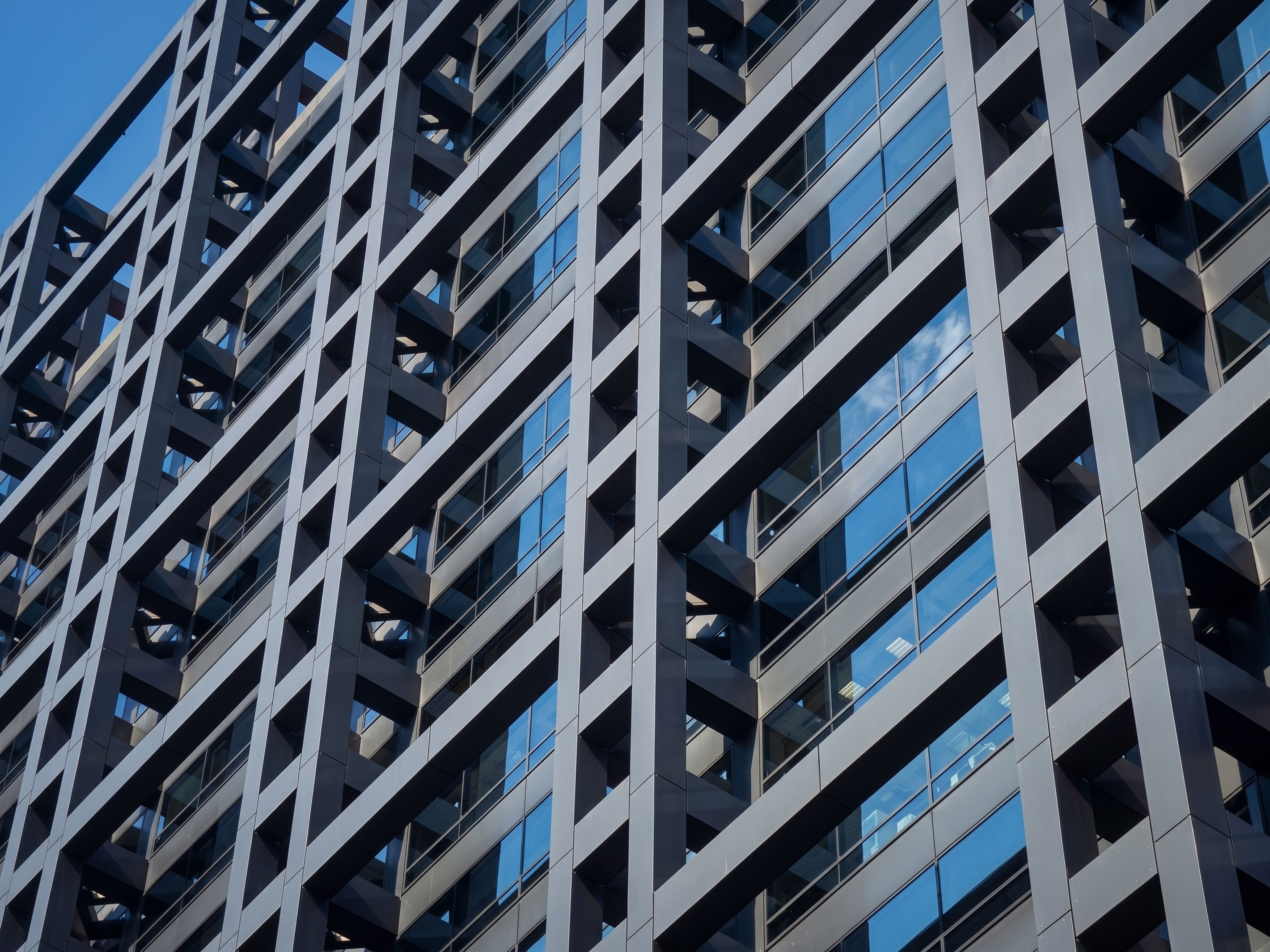 Dynamic perspective of a modern building facade with reflective blue glass windows.
