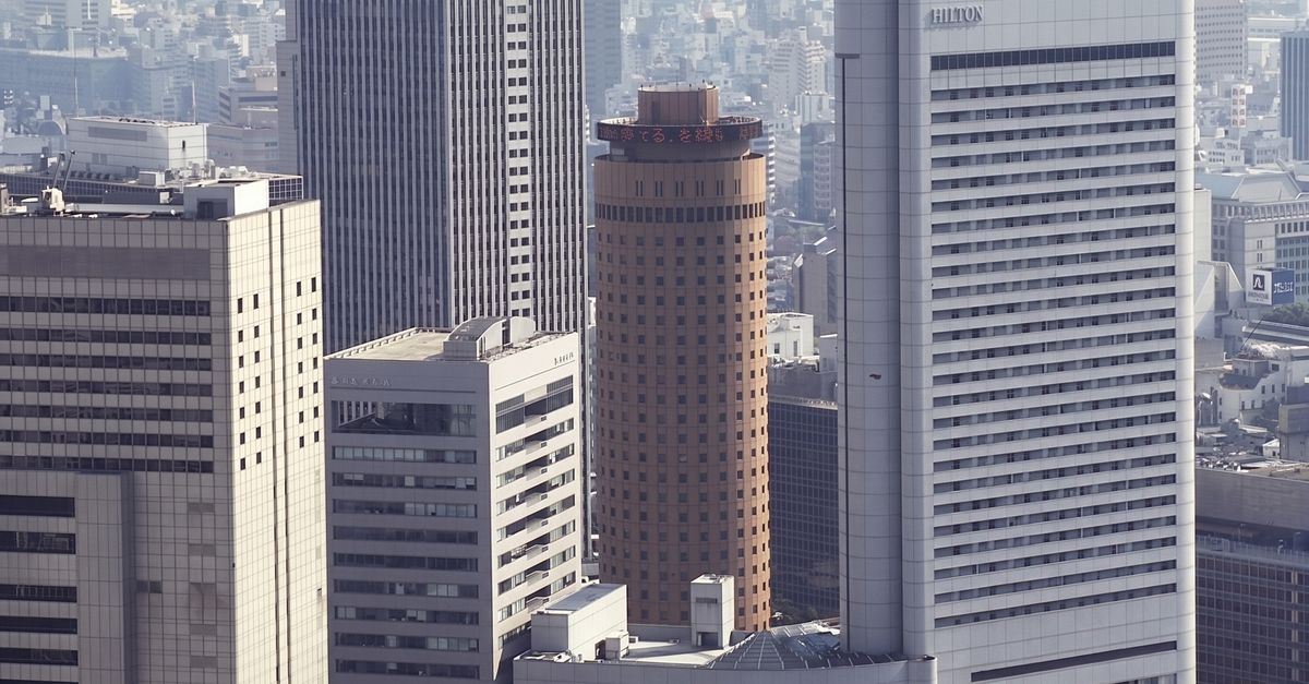 Aerial view of skyscrapers dominating the urban Tokyo skyline on a hazy day.