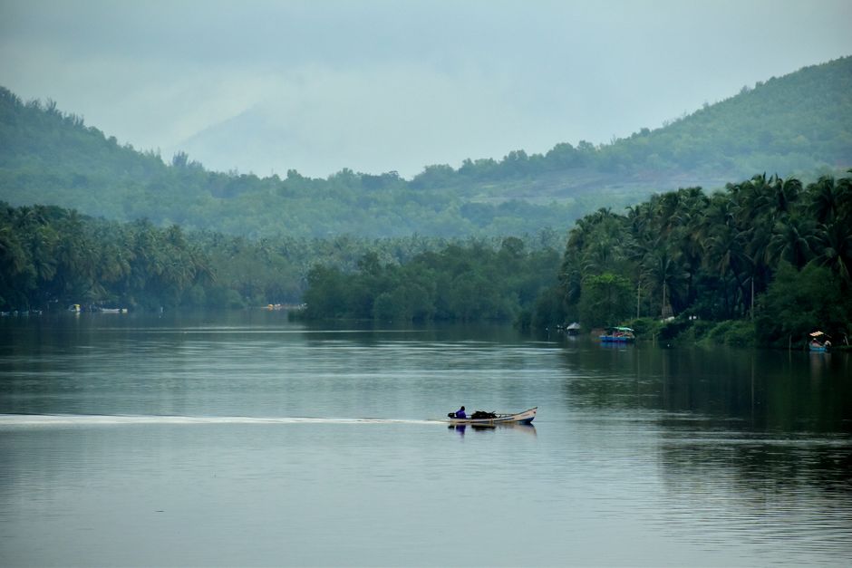 A tranquil scene of a small boat on a serene river in Goa with lush greenery.