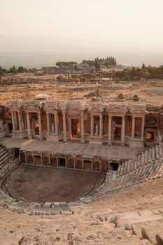 The mesmerizing ancient Roman amphitheater is bathed in soft sunrise hues, located in Hierapolis, Turkey.