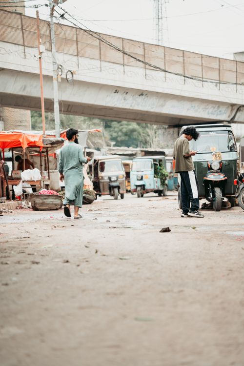 Free A street scene in Karachi with people, auto rickshaws, and vibrant market stalls. Stock Photo