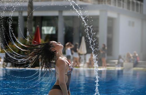 Free A young woman flicking her hair in a swimming pool, capturing a moment of refreshing summer fun. Stock Photo
