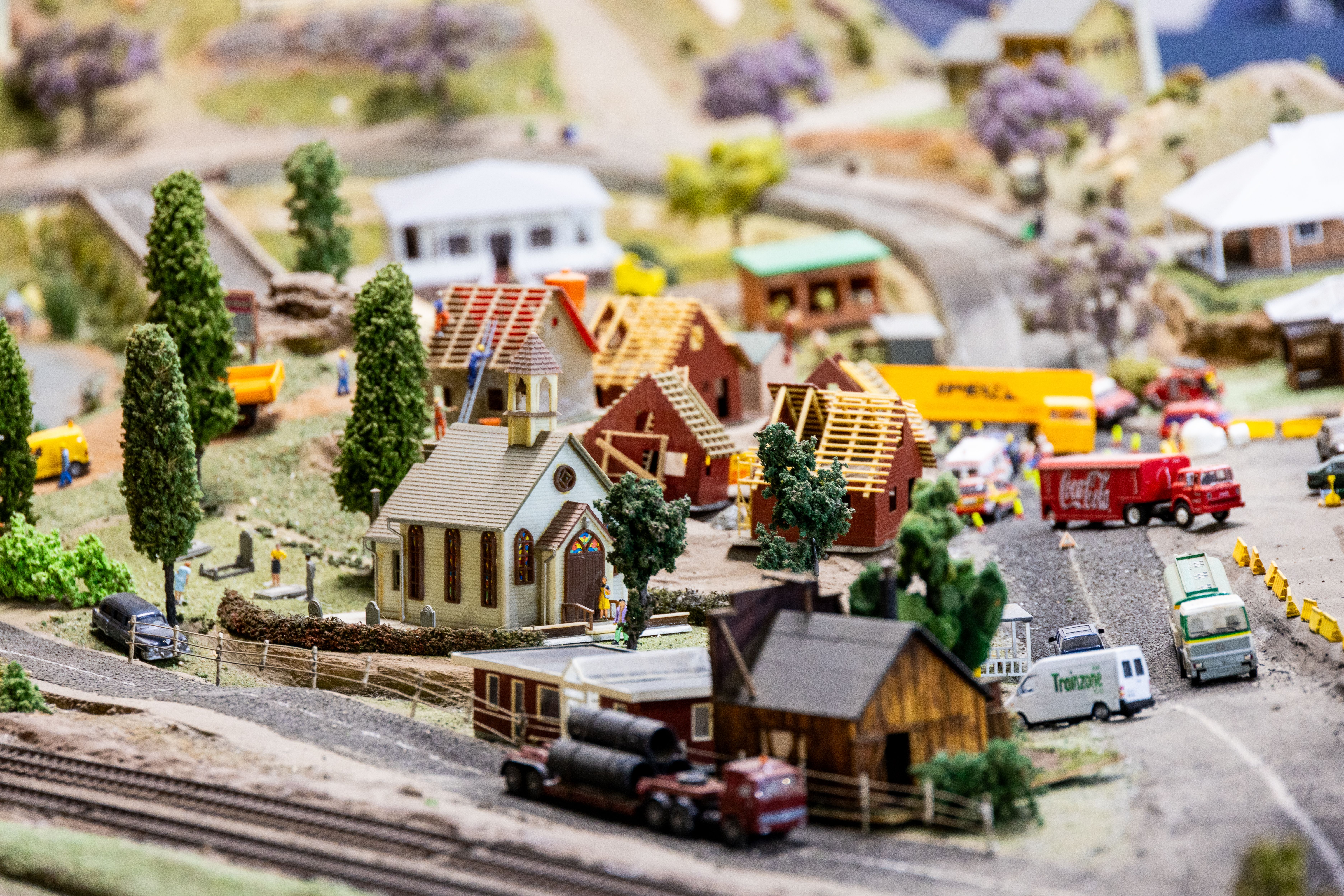 Detailed diorama of a miniature model town featuring a church, vehicles, and construction activity, depicting community life.