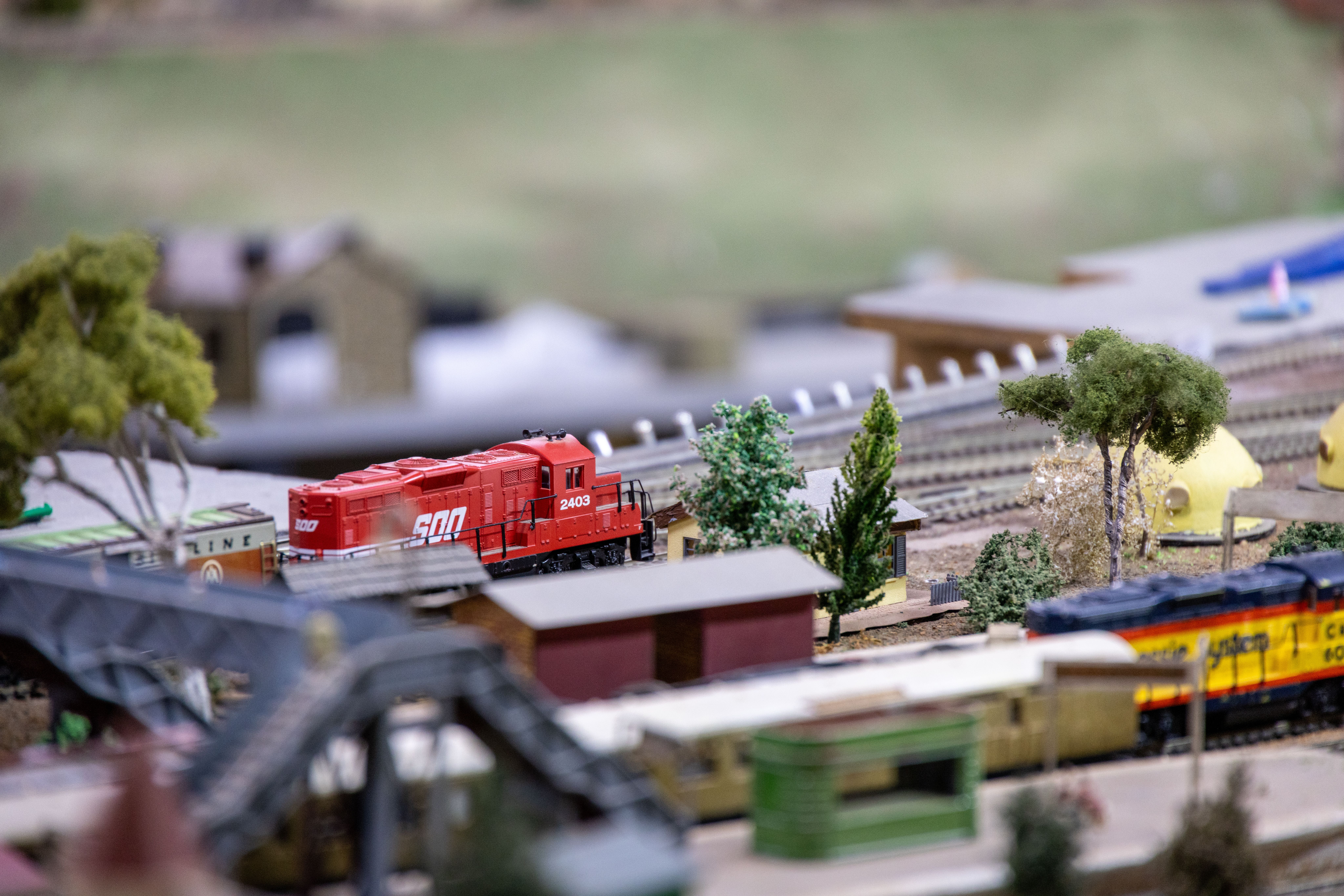 A detailed miniature model train set showcasing a realistic railway scene with two bright locomotives.