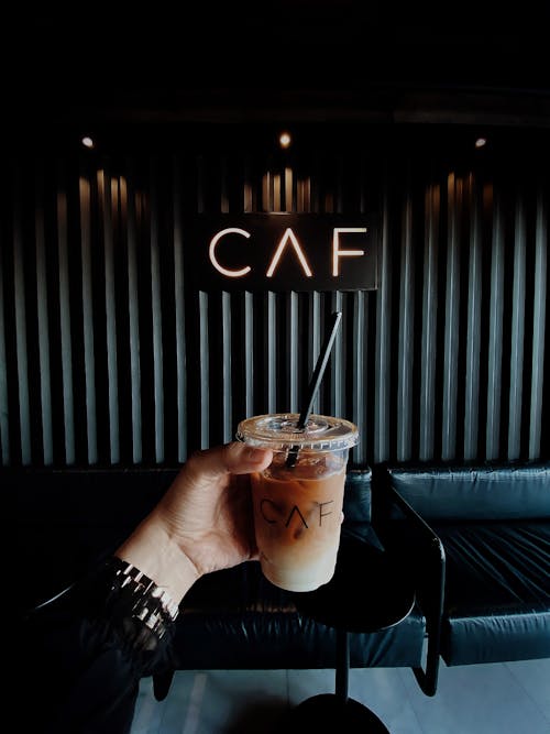 Person Holding Clear Plastic Cup With Brown Liquid