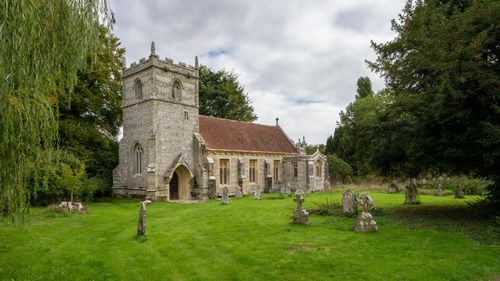 Free Charming rural church with ancient gravestones in a lush green setting. Stock Photo