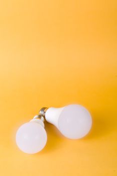Two white light bulbs placed on a bright yellow background creating a minimalist look.