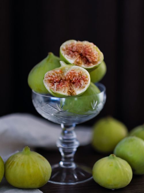 Free Close-up of ripe green figs cut and whole, elegantly arranged in a crystal glass indoors. Stock Photo