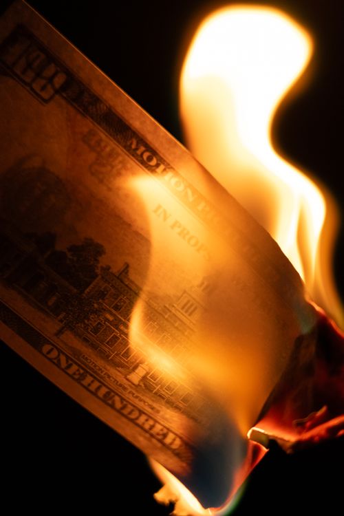 Free A one hundred dollar bill being engulfed in flames, symbolizing financial loss. Stock Photo