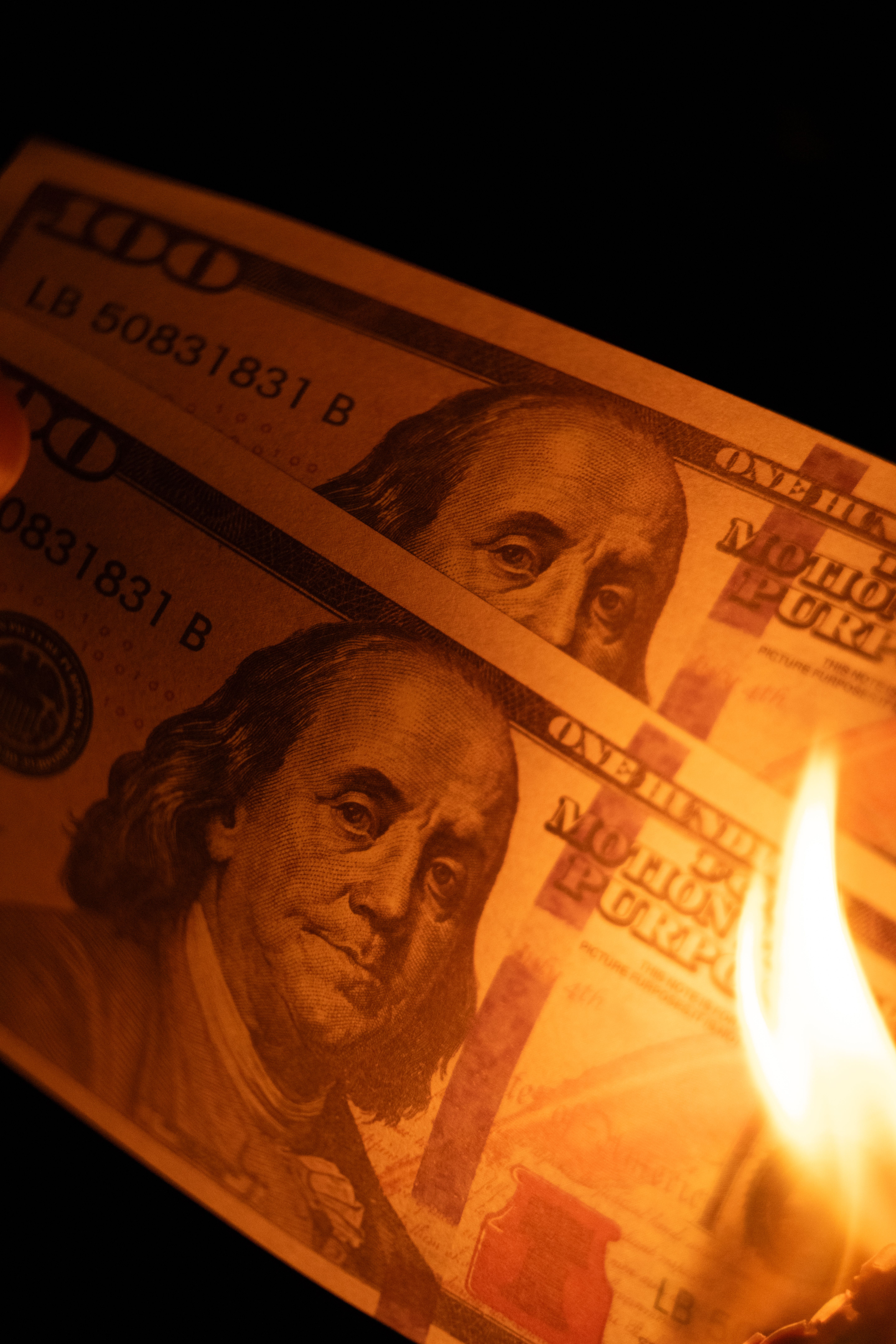 Close-up of burning US hundred dollar bills highlighting financial concepts like inflation or waste.