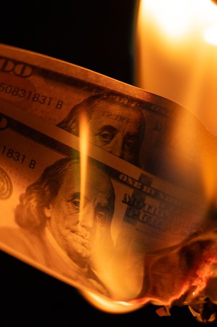 Close-up of a burning hundred dollar bill symbolizing financial loss or crisis.