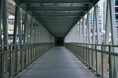 Free A geometric view through a modern walkway in Bangkok, Thailand with city skyscrapers in the background. Stock Photo