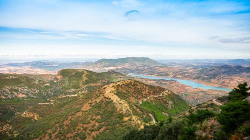 Free Expansive view of mountains, lush greenery, and a winding river under a blue sky. Stock Photo