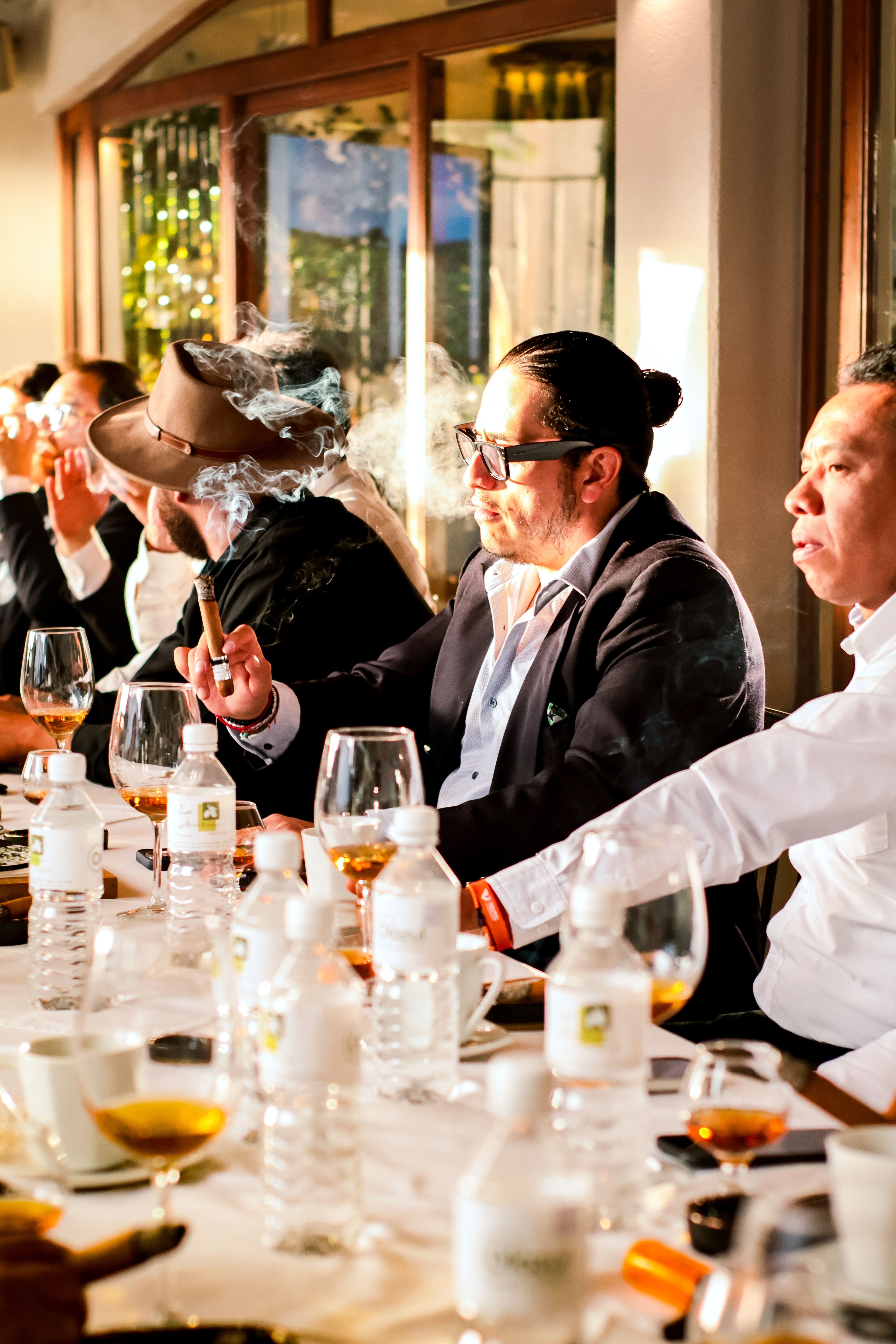 Men enjoying drinks and cigars at a formal event in Huamantla.