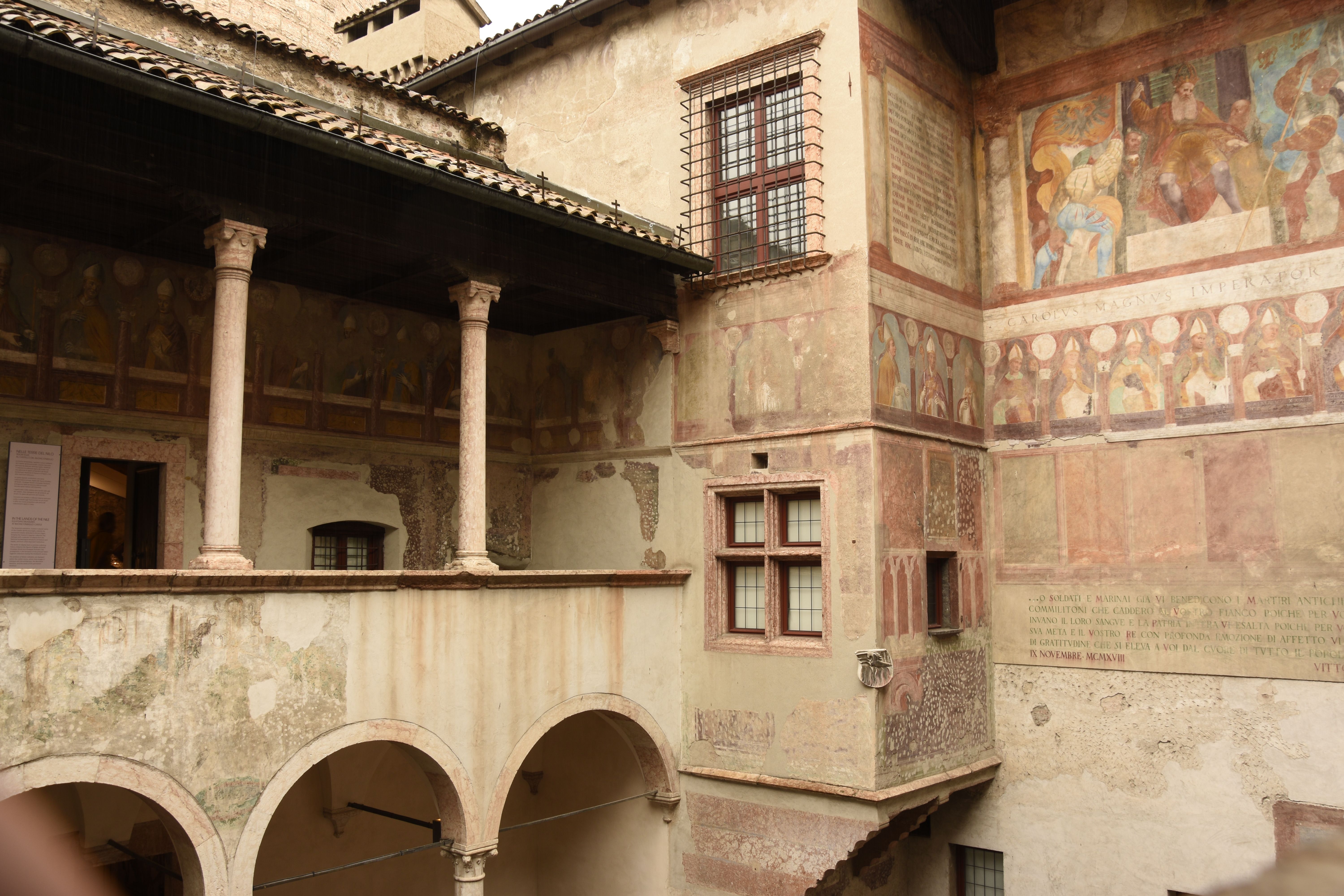Explore stunning frescoes in a medieval courtyard in Trento, Italy, showcasing the artistry of the Renaissance.